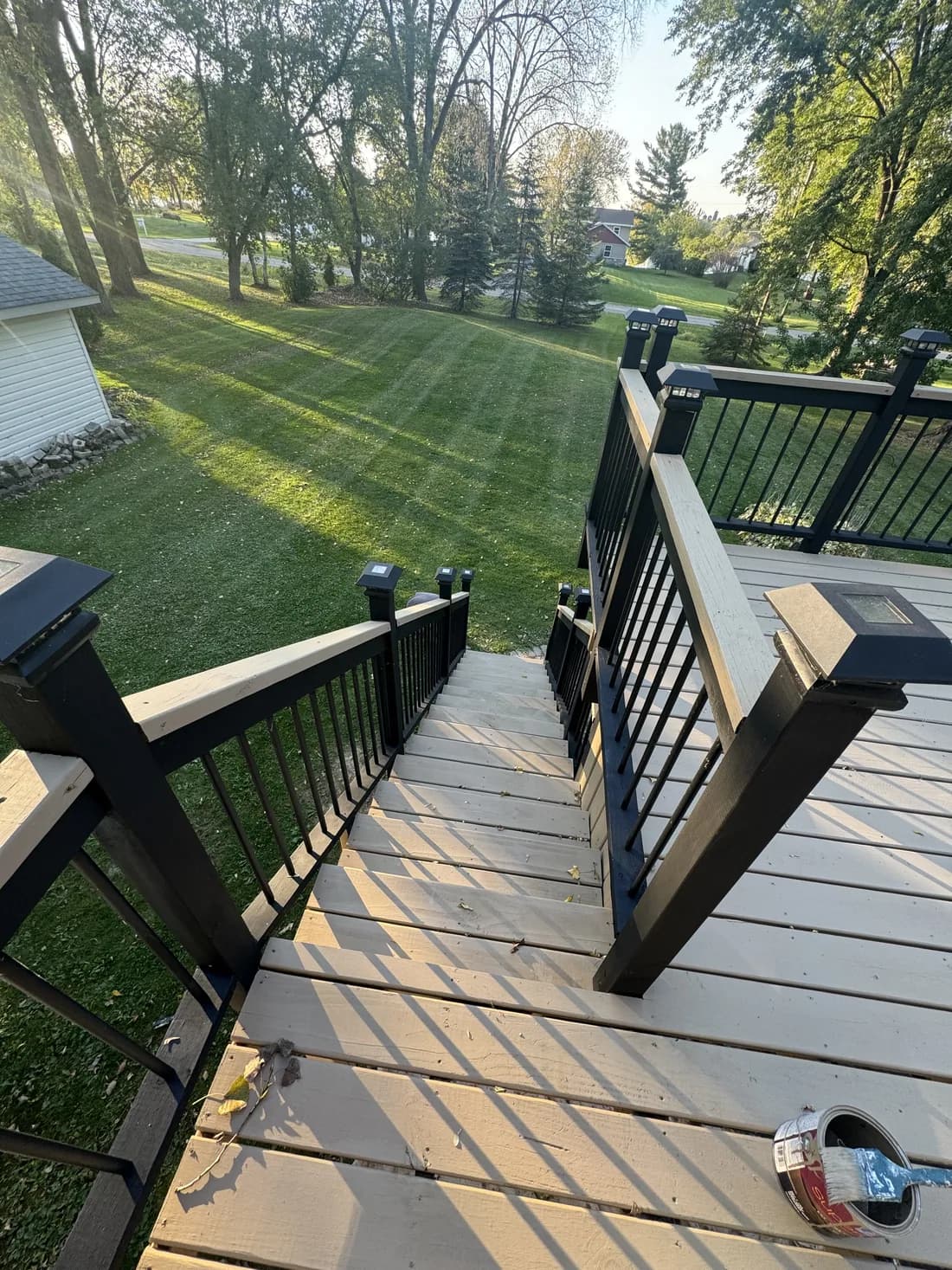 Refinished deck with painted black railings overlooking the yard